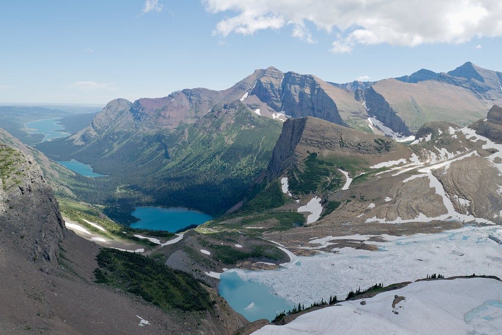 High-angle view overlooking Grinnell Glacier, turquoise alpine lakes, and surrounding mountain ridges in Glacier National Park.
